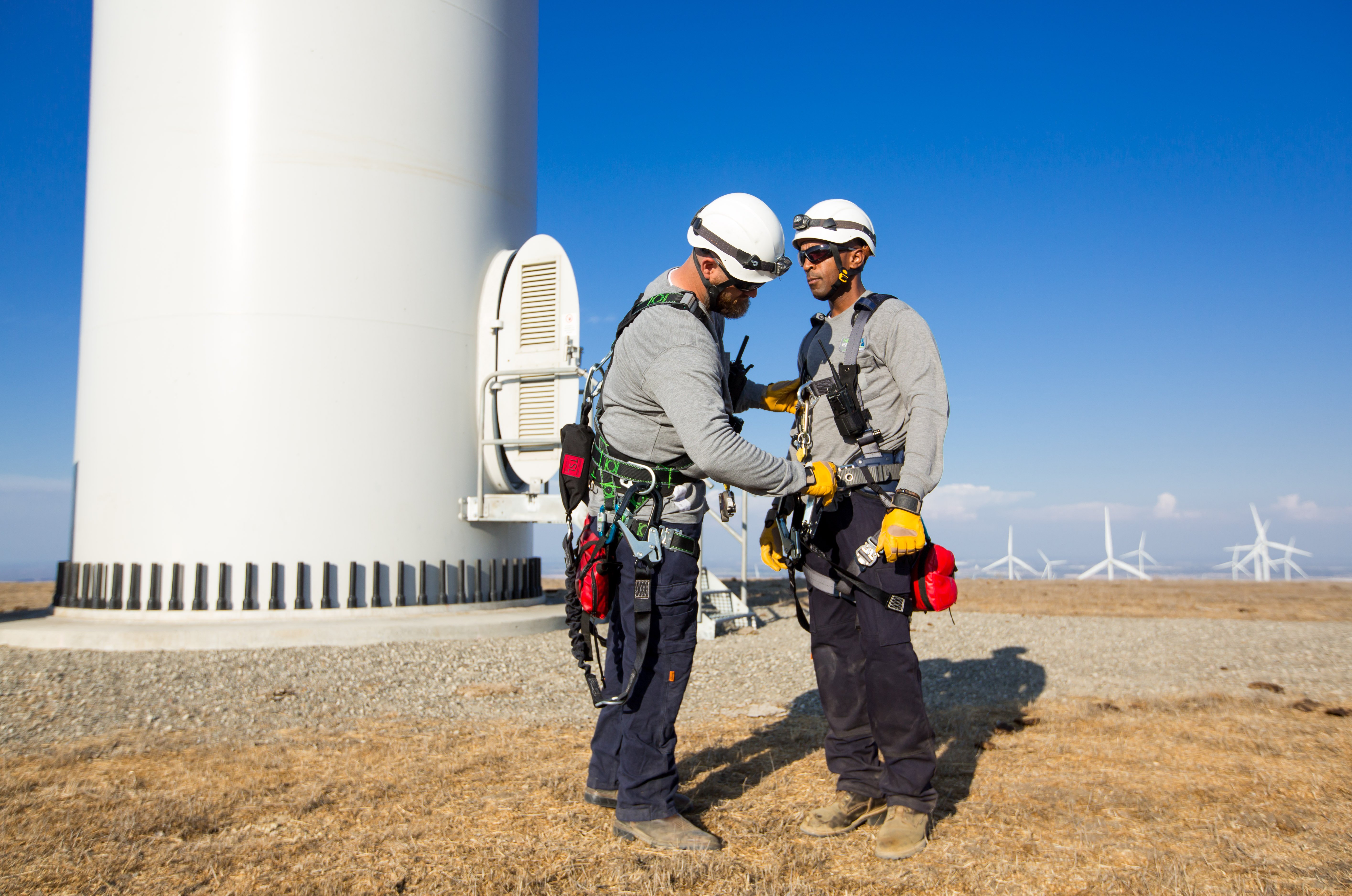 wind techs with gear in front of a wind turbine
