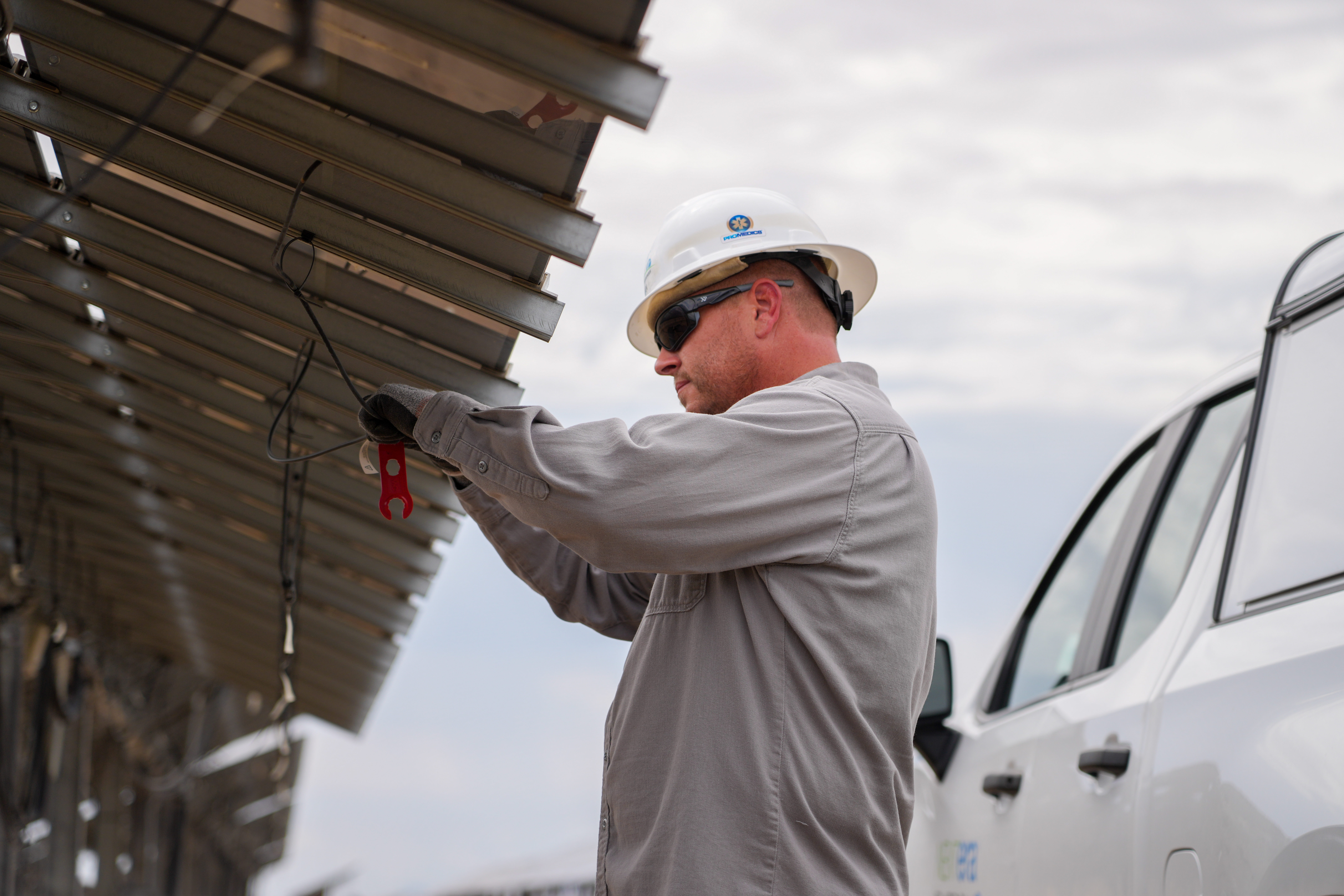 solar technician working on solar panel with truck in background