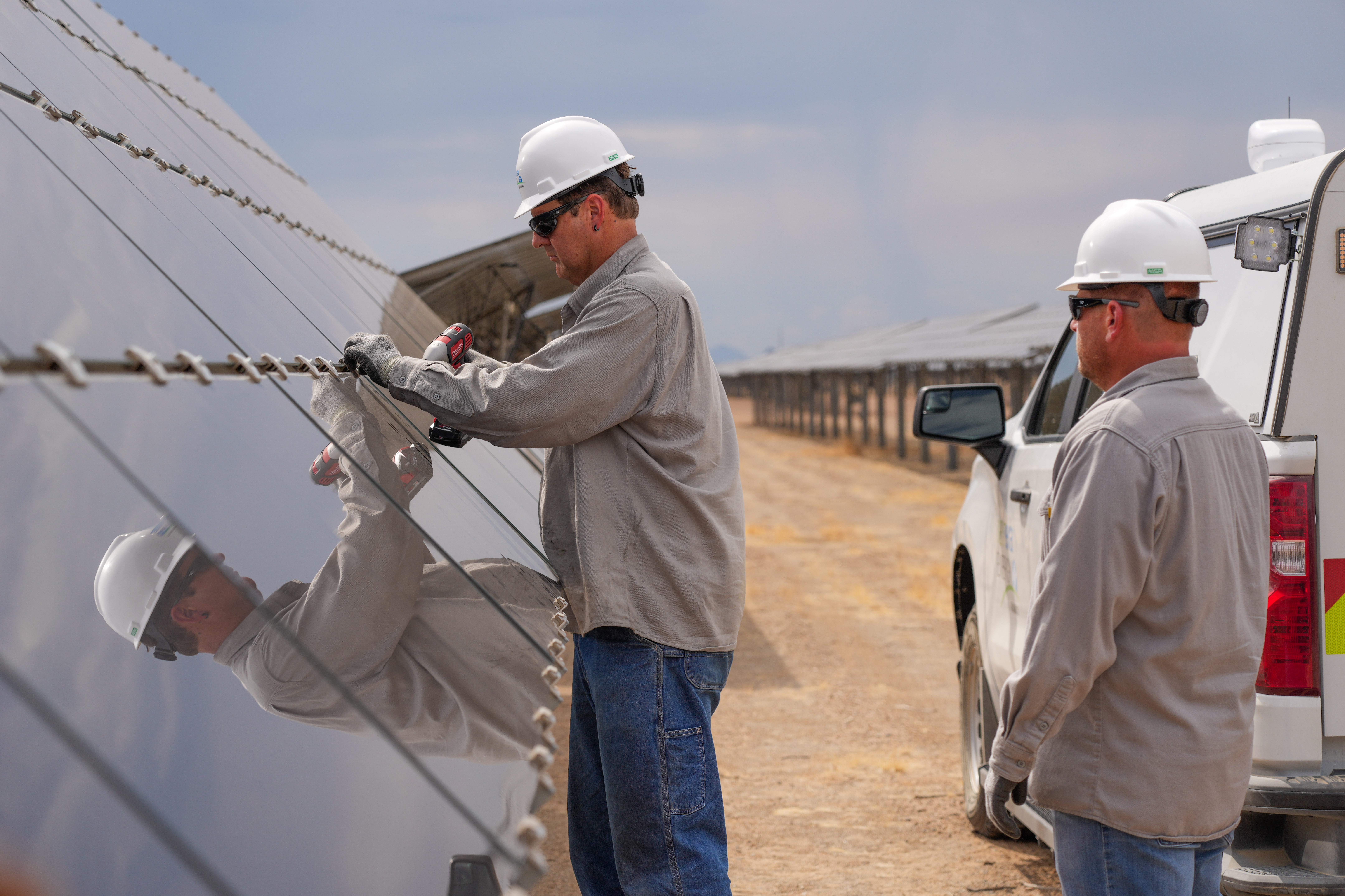 two men in front of a solar panel with truck